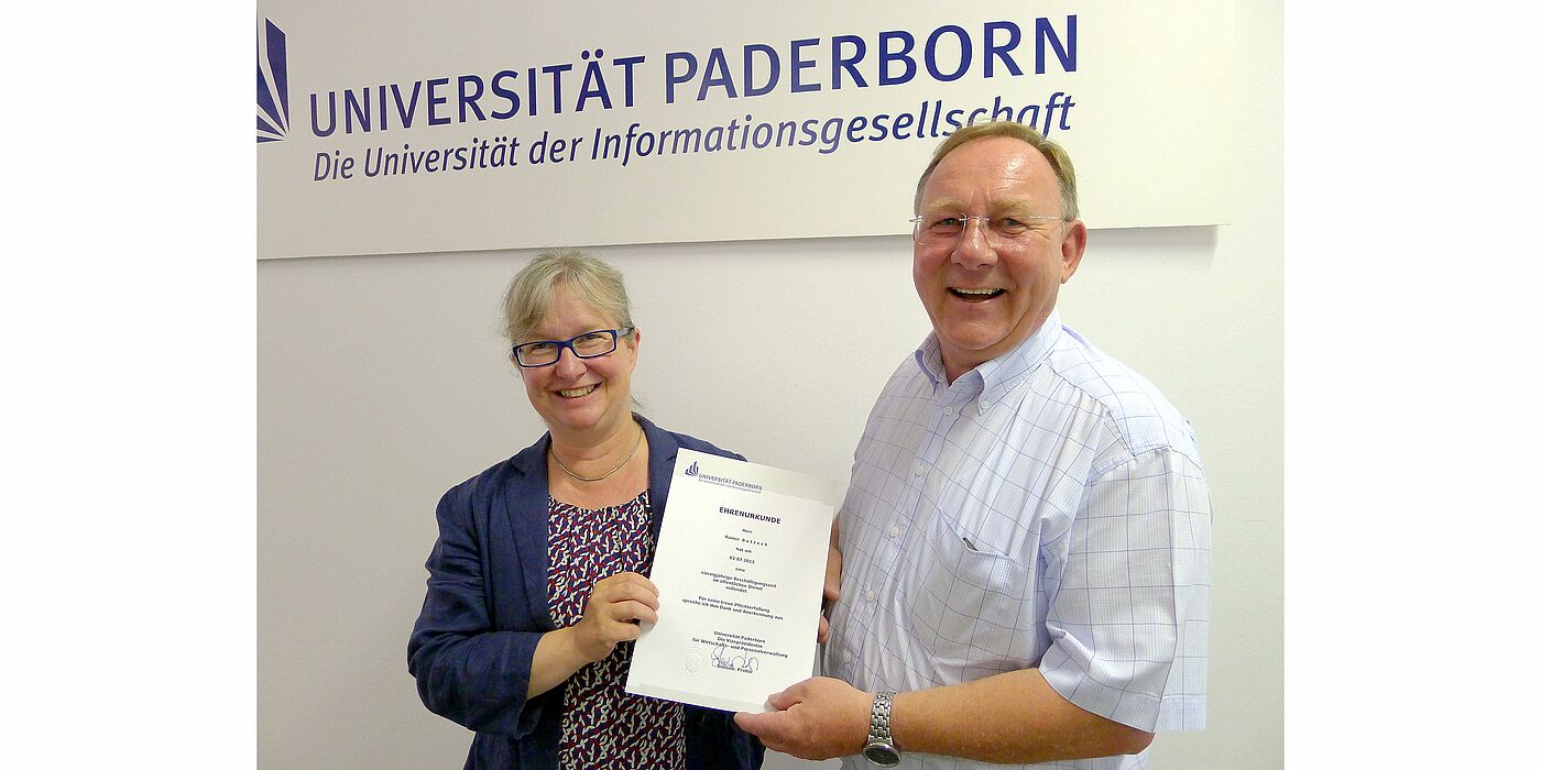 Foto (Universität Paderborn, Tibor Werner Szolnoki): Vizepräsidentin Simone Probst übergibt eine Ehrenurkunde an Rainer Botzeck.