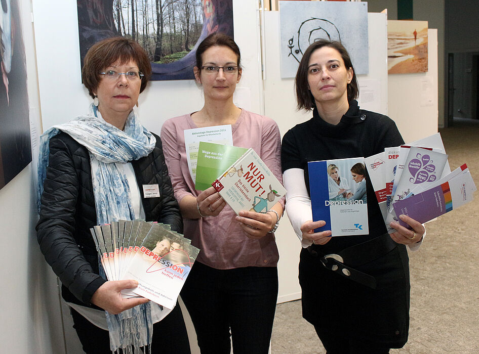 Foto (Universität Paderborn, Heiko Appelbaum): Hildegard Harmeier, Sandra Bischof und Dr. Yvonne Koch (v. l.) werben vor einer Bilderausstellung für einen offensiven Umgang mit der Depression.
