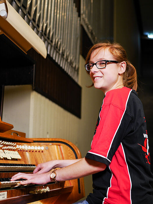 Foto (Universität Paderborn, Johannes Pauly): Event-Physikerin Annika Stellhorn spielt auf der frisch gestimmten Orgel und erklärt die Funktionsweise von Registern und Pfeifen.  