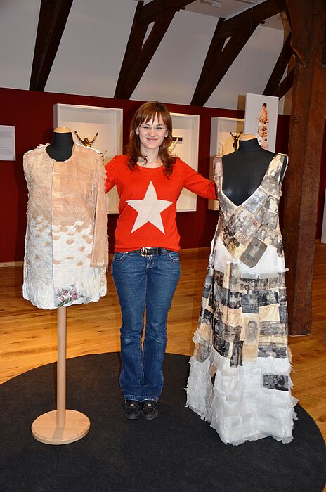 Foto: Helena Arngold mit ihren Werken „Te(e)xtilkleid“ und „Kleid meines Lebens“ (v. l. n. r.)