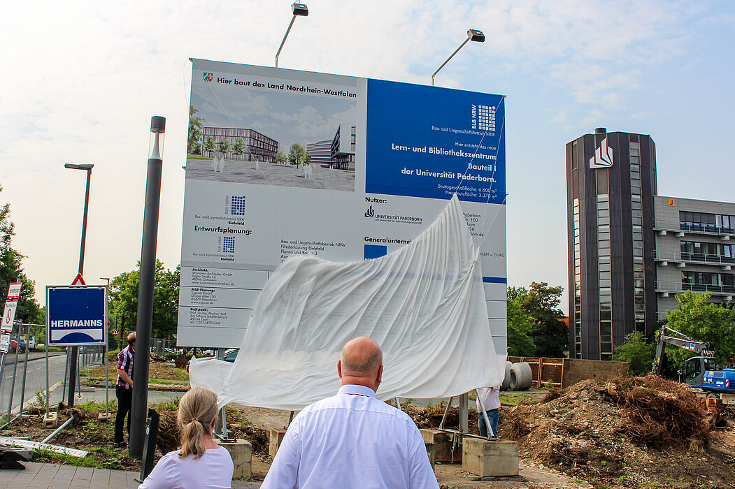 Foto (Universität Paderborn, Johannes Pauly): Das Tuch fällt – die Enthüllung des Bauschildes vermittelt einen ersten Eindruck vom neuen Gebäude.