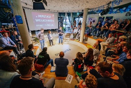 In garage33, the start-up incubator of Paderborn University, numerous people interested in starting a business and founders sit in a circle and listen to a lecture.