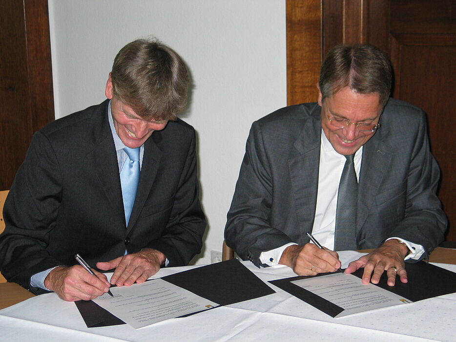 Foto (Ramona Wiesner): Die von Hella gestiftete Juniorprofessur für die Universität Paderborn wird vertraglich besiegelt durch Professor Dr. Nikolaus Risch (links) und Dr. Jürgen Behrend.