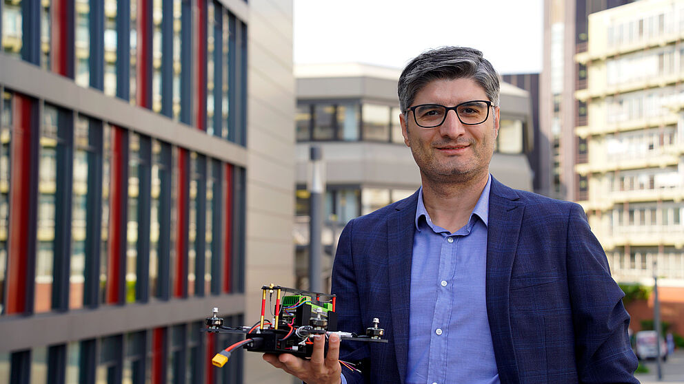 Prof. Dr. Erdal Kayacan mit einem Flugroboter auf dem Campus der Universität Padeborn.