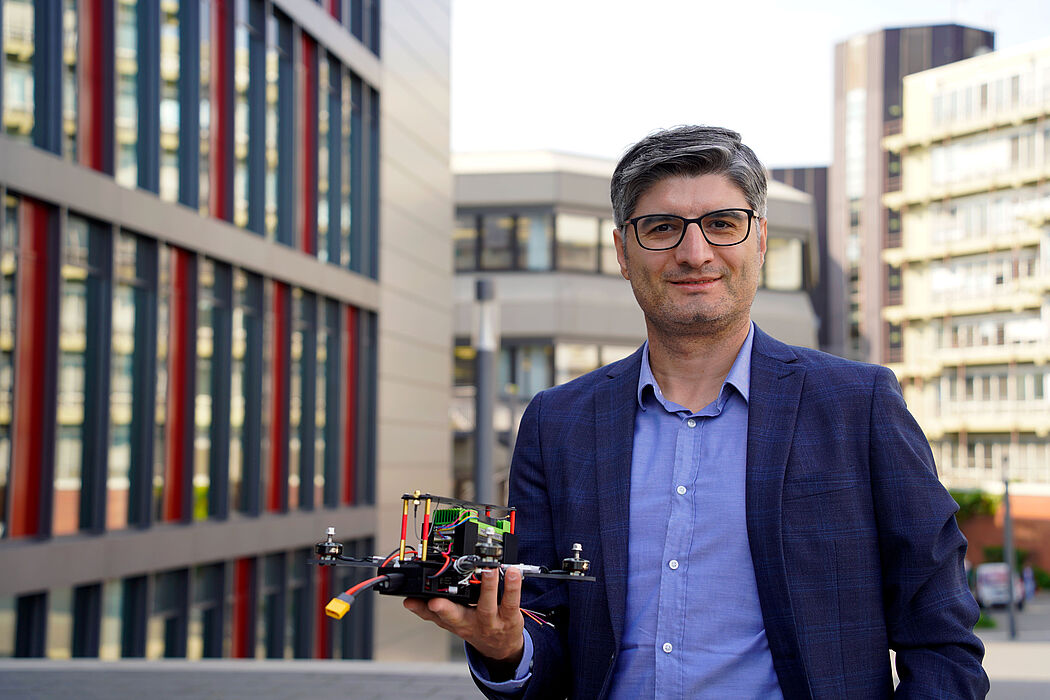 Prof. Dr. Erdal Kayacan mit einem Flugroboter auf dem Campus der Universität Padeborn.