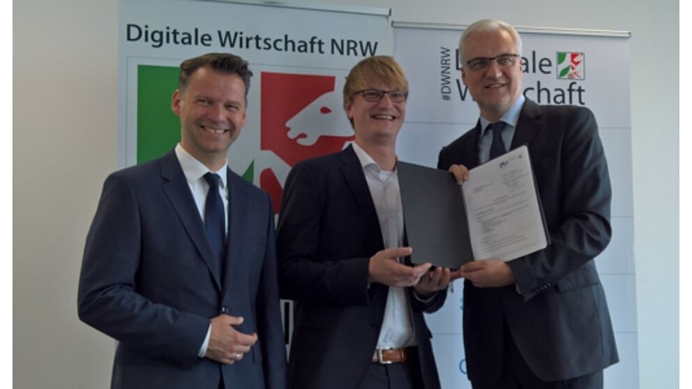 Foto (Universität Paderborn, TecUP): Prof. Dr. Tobias Kollmann (l.) und NRW-Wirtschaftsminister Garrelt Duin (r.) überreichen Dr. Sebastian Vogt (m.), Geschäftsführer von TecUP, den offiziellen Förderbescheid.