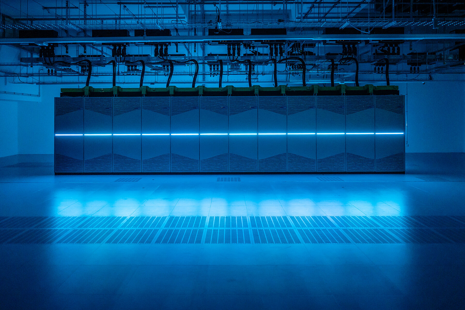 Der Supercomputer Noctua 2 des PC2 im Gebäude X, die mittig angebrachte LED-Linienbeleuchtung der einzelnen Serverschränke taucht den Raum in blaues Licht.