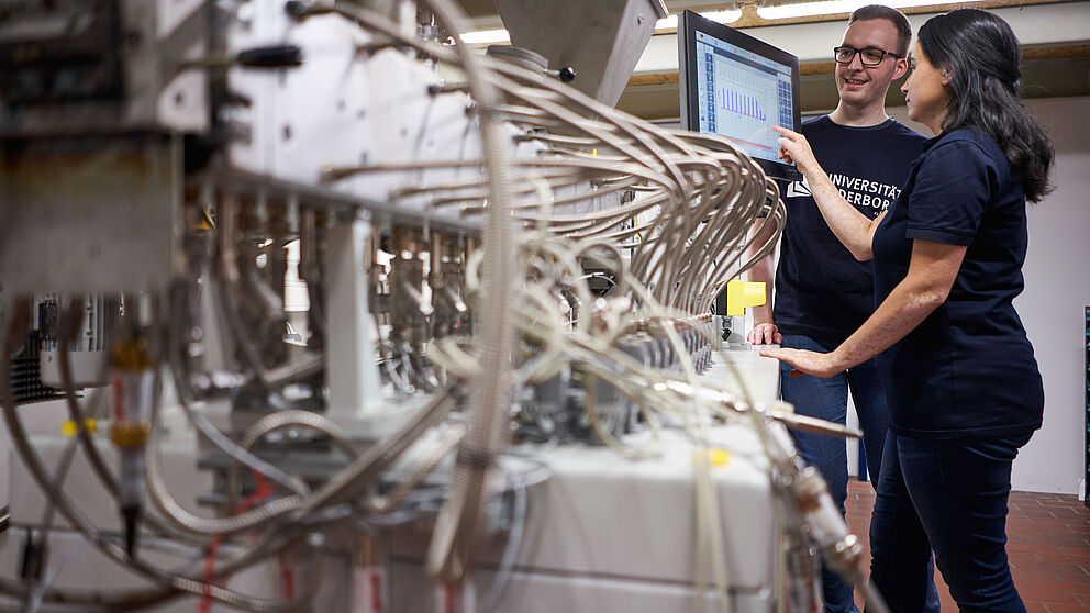 Eine Wissenschaftlerin und ein Wissenschaftler der Universität Paderborn arbeiten gemeinsam an einer Maschine.