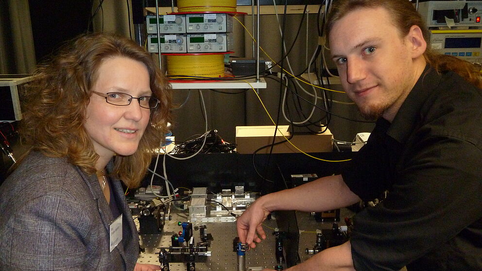 Foto (Universität Paderborn): Christine Silberhorn und Andreas Schreiber präsentieren stolz ihr neues Experiment zur Realisierung von Quantenspaziergängen.