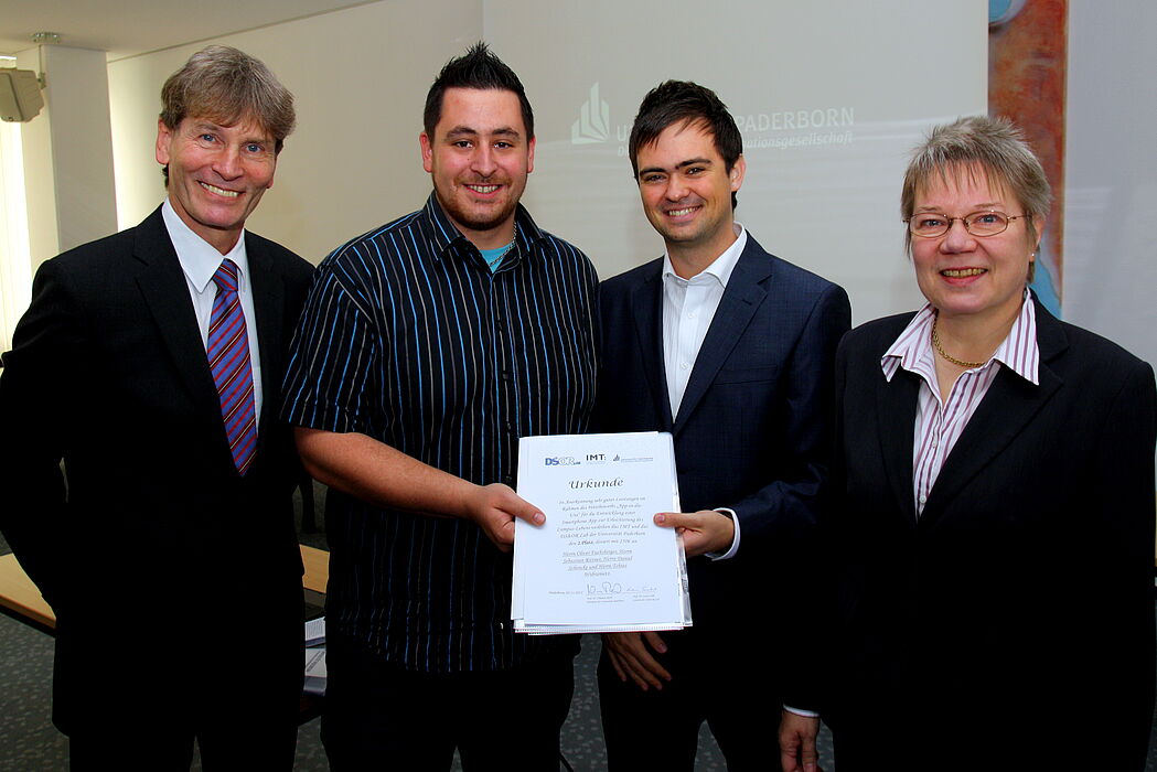 Foto (Universität Paderborn, Patrick Kleibold): Prof. Dr. Nikolaus Risch und Prof. Dr. Leena Suhl überreichen die Urkunde für den zweiten Preis im Wettbewerb „App in die Uni“ an Oliver Fuchsberger und Sebastian Rittner.