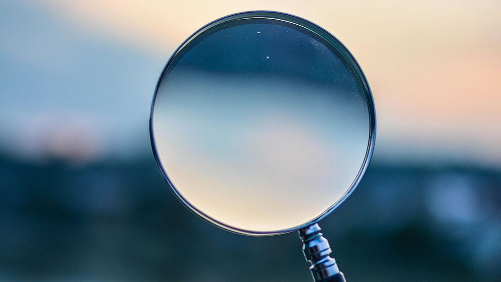 Hand, die Lupe hält