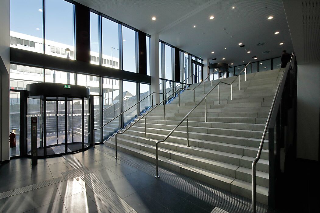 Foto (Espendiller+Gnegel): Das neue Gebäude I passt sich der Topografie des Vorplatzes an. Die Treppe im Außenbereich setzt sich im Inneren des Gebäudes fort. Im Hintergrund ist das bereits im Jahr 2013 fertiggestellte Gebäude Q erkennbar.