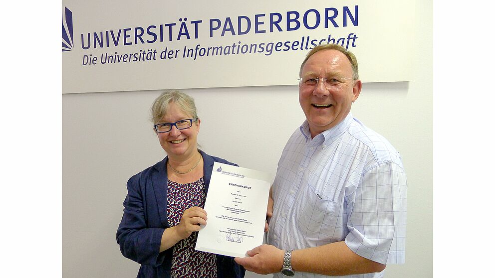 Foto (Universität Paderborn, Tibor Werner Szolnoki): Vizepräsidentin Simone Probst übergibt eine Ehrenurkunde an Rainer Botzeck.