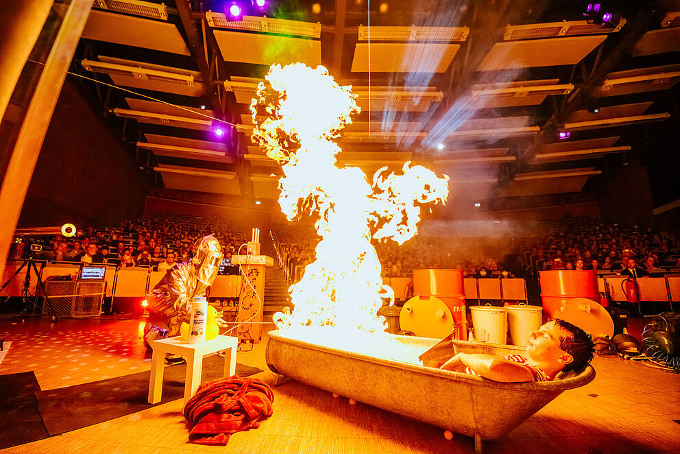 Fynn Bremser takes a relaxing bath in the burning bathtub in front of visitors to the event physics show.