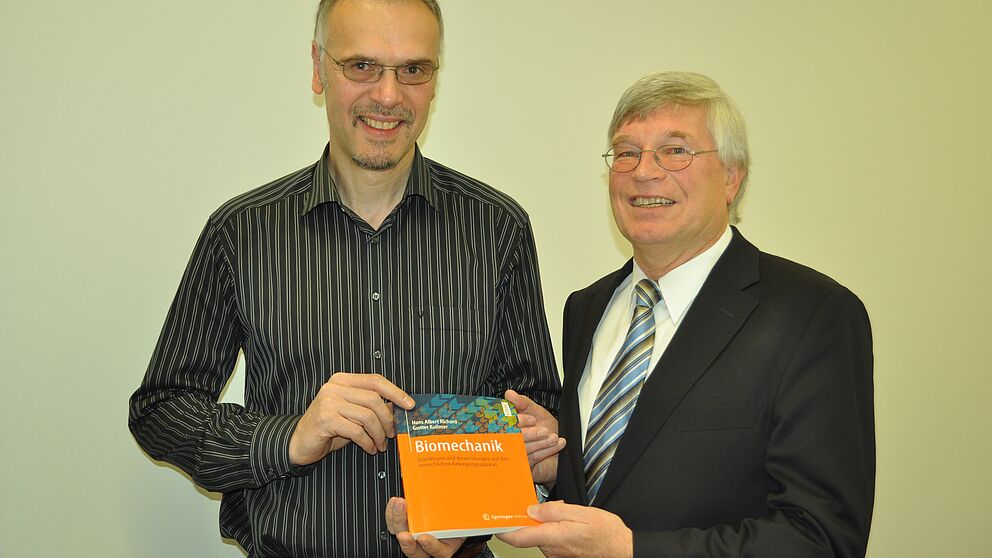 Foto (Universität Paderborn): Prof. Dr.-Ing. Gunter Kullmer (li.) und Prof. Dr.-Ing. Hans Albert Richard mit dem neuen Fachbuch „Biomechanik“.