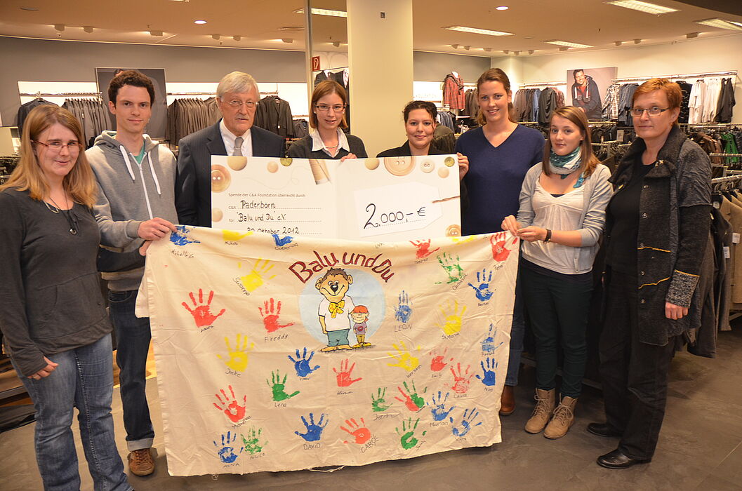 Foto (Stadt Paderborn): Bei der Spendenübergabe (v. l.): die Studierenden Julia Schlichting und Thomas Hüsgens, Bürgermeister Heinz Paus, Studentin Imke von Bargen, C&A-Filialleiterin Manuela Rodorff, die Studentinnen Maria Rockenfeller und Johanna Eic