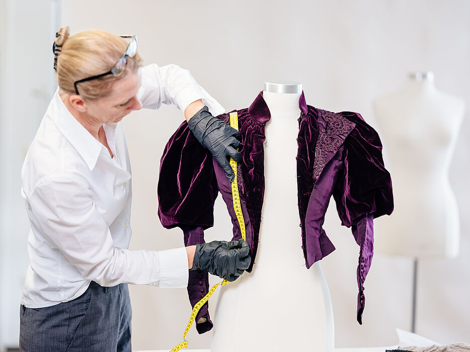 Foto (Universität Paderborn, Besim Mazhiqi): Prof. Dr. Kerstin Kraft von der Universität Paderborn untersucht historische Kleidungsstücke, um daraus Rückschlüsse auf frühere Bewegungsformen zu ziehen.
