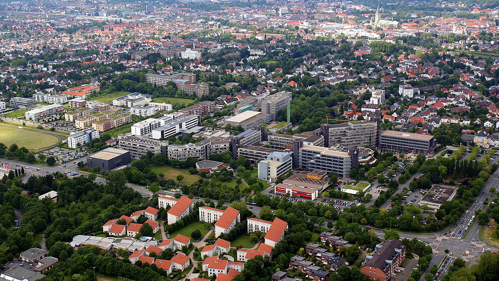 Foto (Universität Paderborn, Patrick Kleibold): Luftbild der Uni vom 14. Juni 2013. Im Hintergrund die Stadt und der Paderborner Dom.