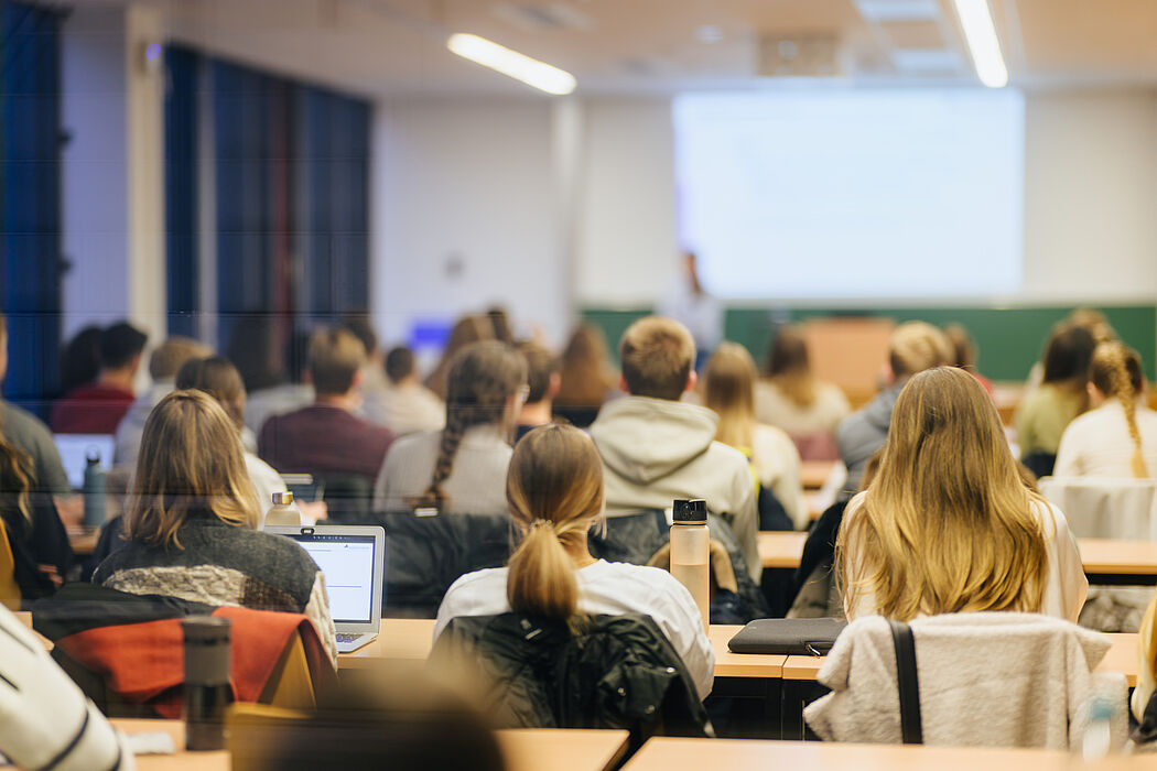 Young people sit in a seminar room and look ahead