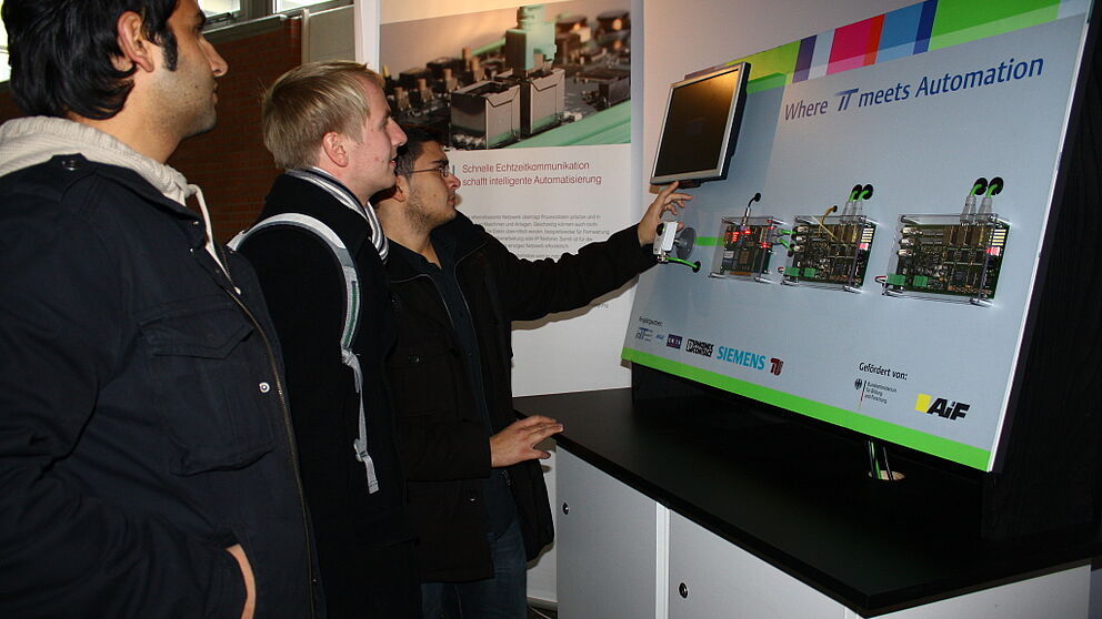 Foto: Die Studenten Umut Tanir (24), Johannes Hölper (23) und Ilker Durmaz (21) informieren sich zum Thema "Where IT meets Automation".