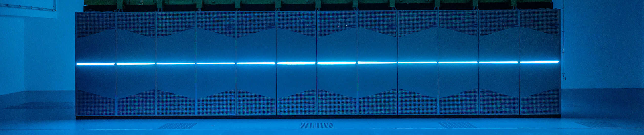 The PC2's Noctua 2 supercomputer in Building X, the center-mounted LED line lighting of the individual server cabinets bathes the room in blue light