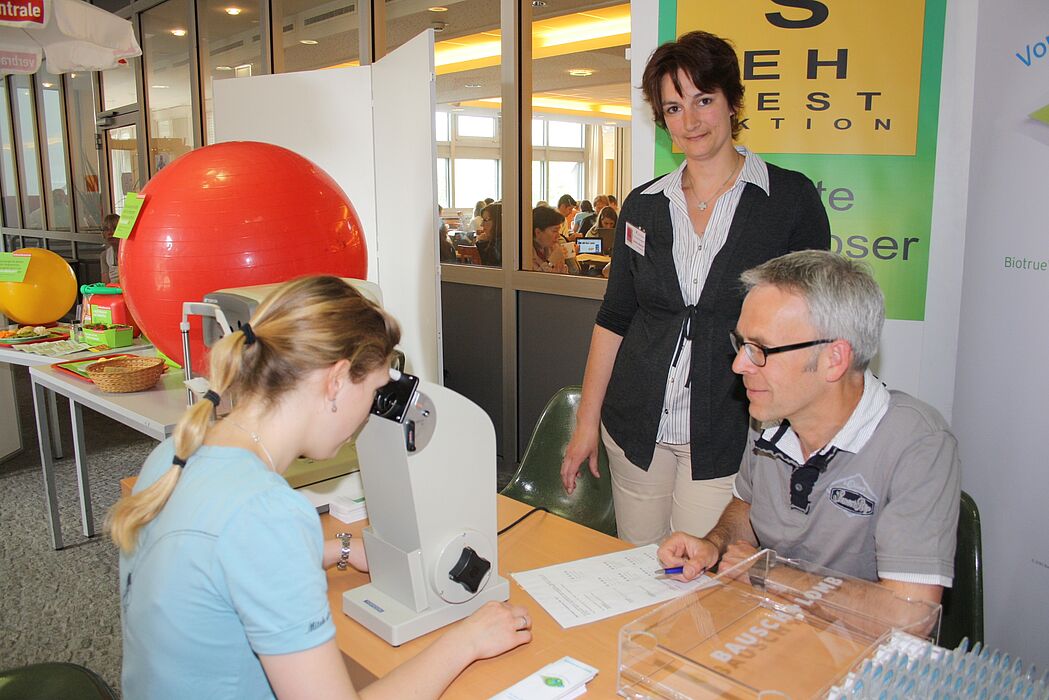Foto (Universität Paderborn, Heiko Appelbaum): Natalie Botsch (links) und die Organisatorin Sandra Bischof nutzten die Uni-Gesundheitstage auch für einen Sehtest bei Augenoptikermeister Reinhard Tölle.