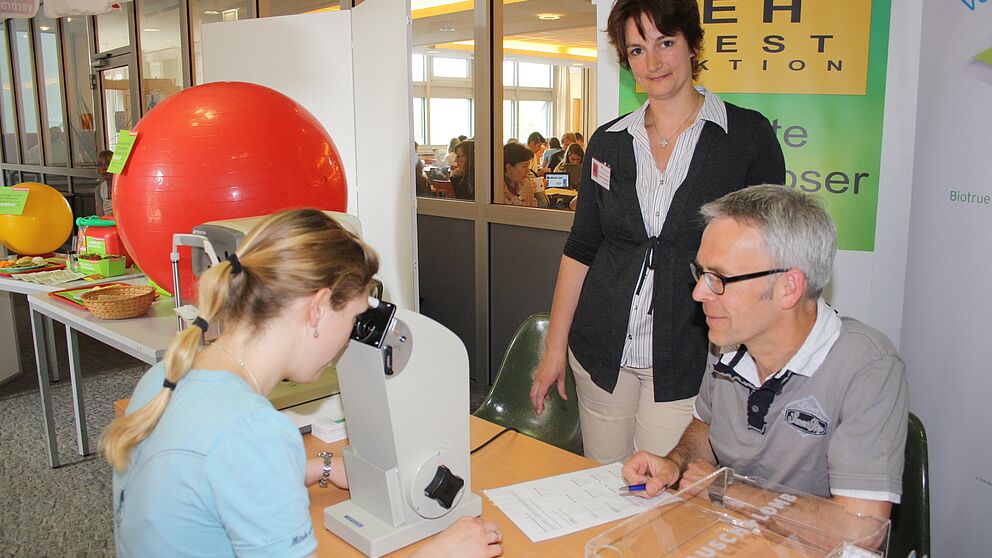 Foto (Universität Paderborn, Heiko Appelbaum): Natalie Botsch (links) und die Organisatorin Sandra Bischof nutzten die Uni-Gesundheitstage auch für einen Sehtest bei Augenoptikermeister Reinhard Tölle.