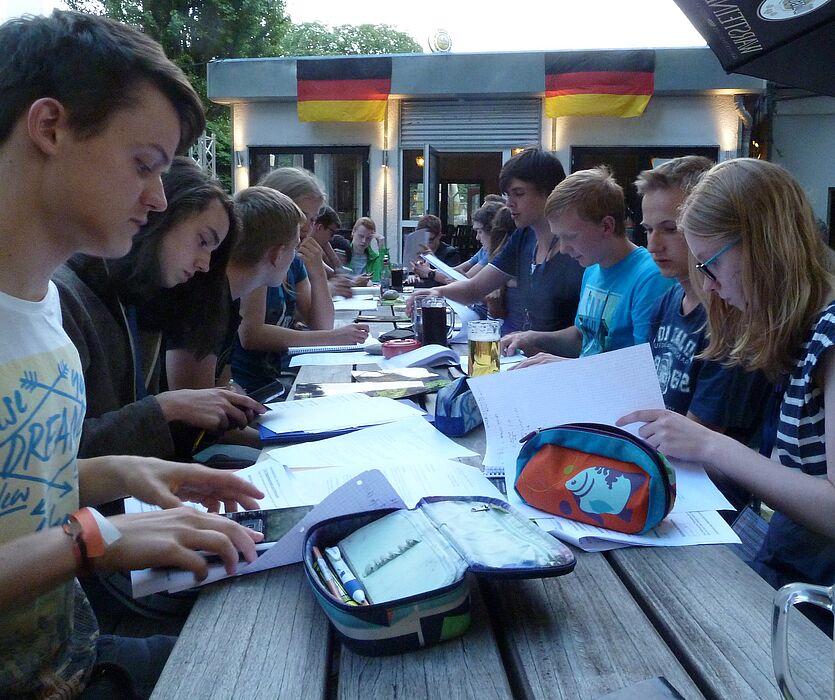 Foto (Universität Paderborn, Department Physik): Studentenfeeling inklusive: Die SommerCamper sitzen entspannt im Biergarten und diskutieren nebenbei die Hausaufgaben zur Vorlesung.