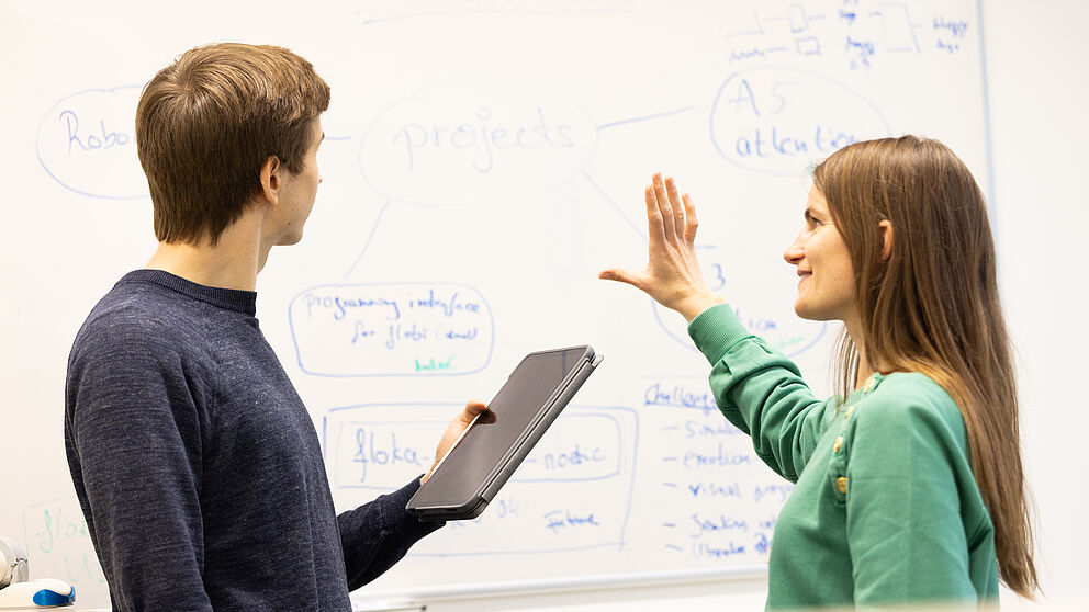 zwei Menschen vor einer Tafel