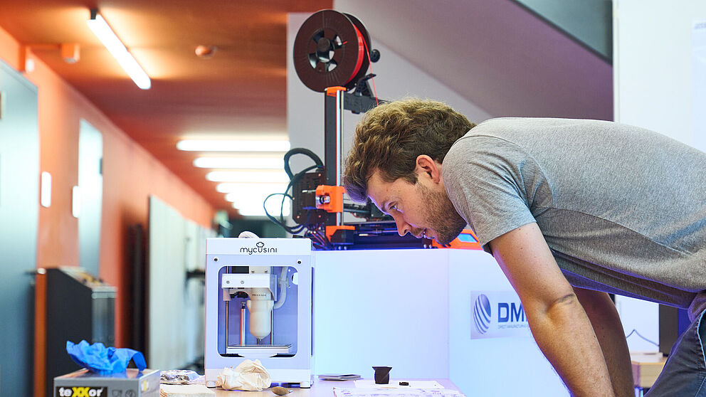 A man looks at various 3D printing materials lying on a table.