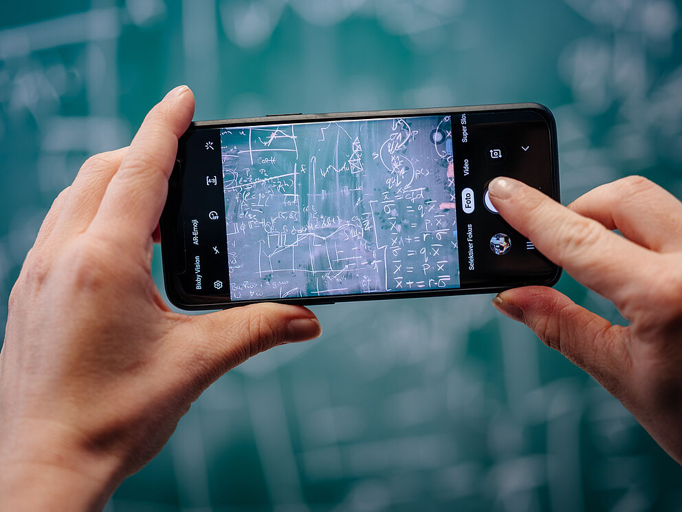 Handy fotografiert vollgeschriebene Tafel
