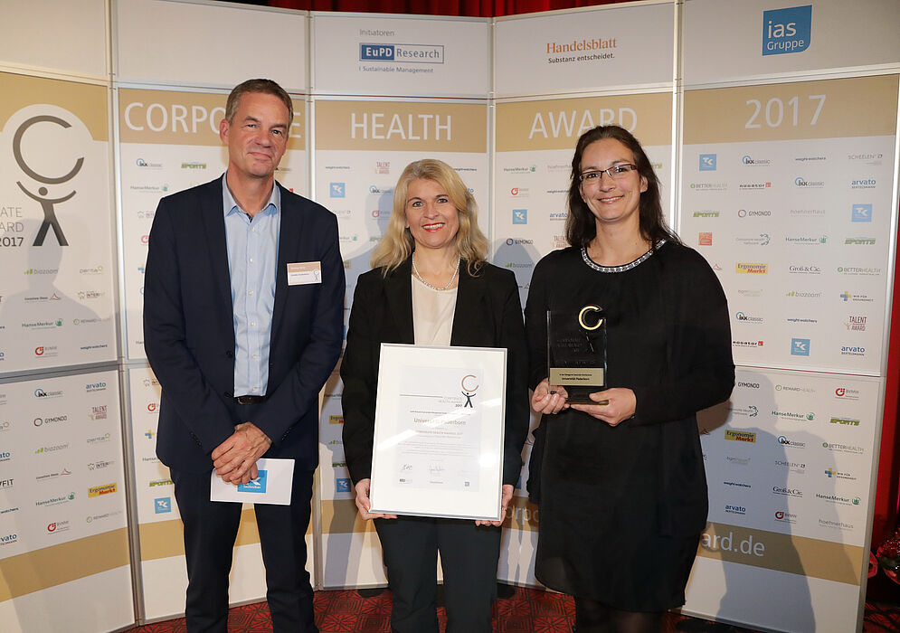 Foto (EuPD Research Sustainable Management GmbH): (v. l.) Thomas Holm, Leiter des Gesundheitsmanagements bei der Techniker Krankenkasse, überreichte den Preis an Diana Riedel und Sandra Bischof.