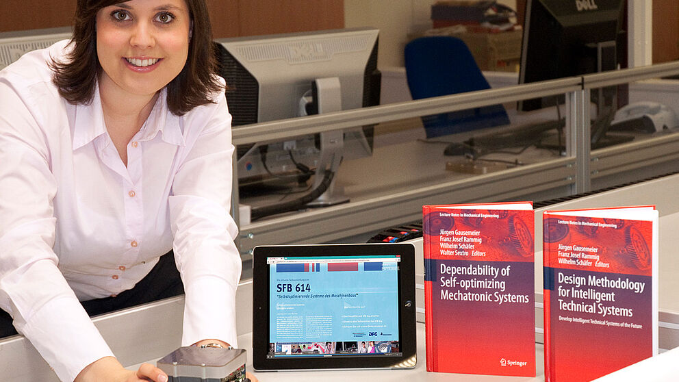 Foto (Universität Paderborn, Heinz Nixdorf Institut): Mareen Vaßholz, Geschäftsführerin des SFB 614, mit einem Miniaturroboter, der als Demonstrator für die Ergebnisse der Forschungsarbeiten sowie der Abschlusspublikationen dient.