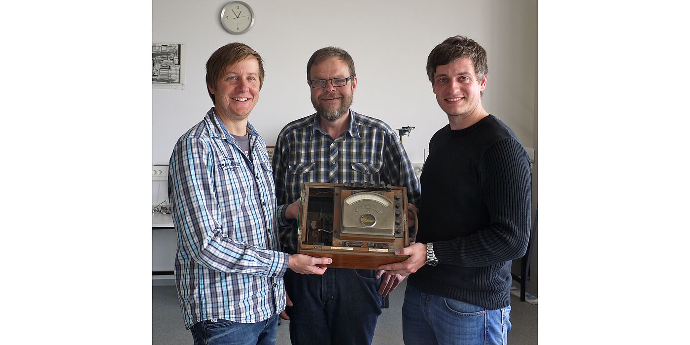 Foto (Heike Probst) (v. l. n. r.): Dr. Marc Sacher und Wilfried Bröckling (beide Uni Paderborn) und Tim Müller, Physik-Lehrer am Reismann-Gymnasium, freuen sich über die Übergabe des historischen Messgeräts und die geplante Kooperation im Rahmen der 