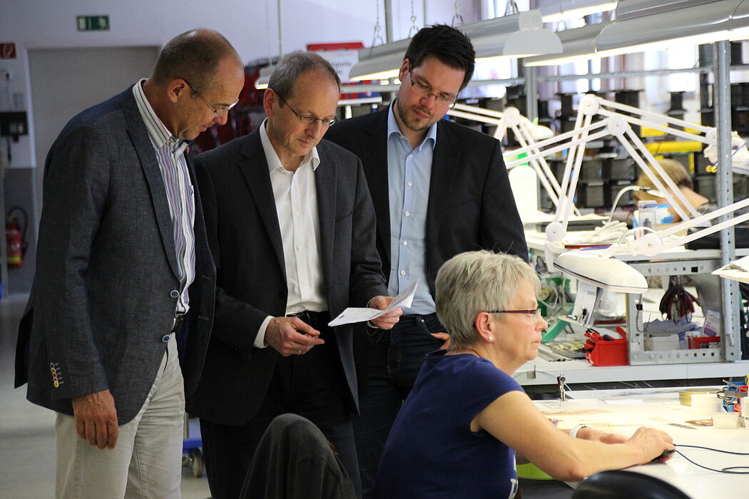 Foto: Wolfgang Kaiser (Friedr. Freek GmbH, links) zeigt Prof. Dr. Niclas Schaper und Projektmitarbeiter Julian Decius (jeweils Universität Paderborn) den Einsatzort der im Projekt StraKosphere konzipierten Kompetenzmanagementtabelle.