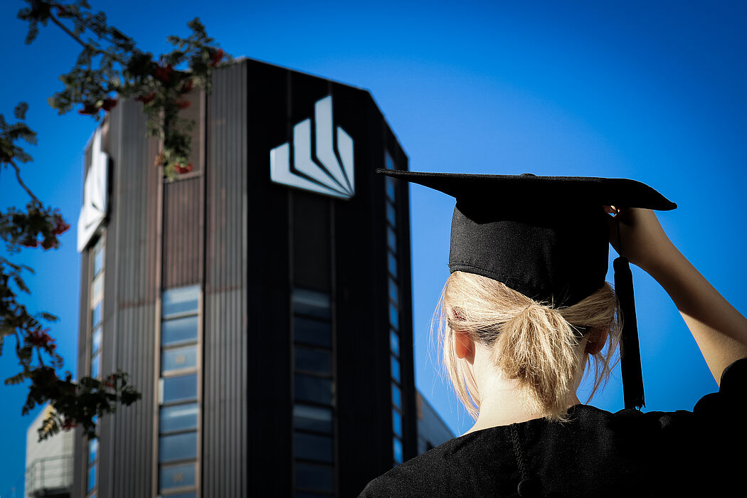 Absolventin steht vor Uni-Gebäude