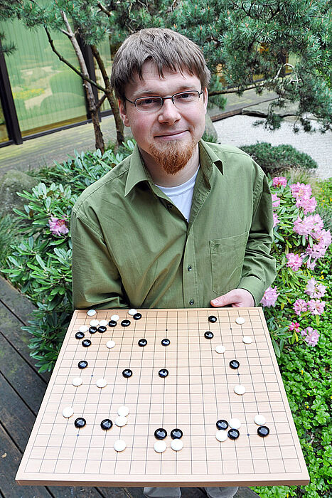 Foto (Katharina Bätz): Lars Schäfers zeigt eine Spielsituation auf einem Go-Brett.