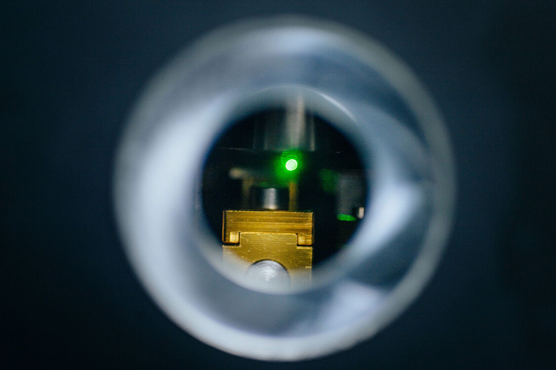 View through a vignette of a technical device. In the middle you see green laser light. 