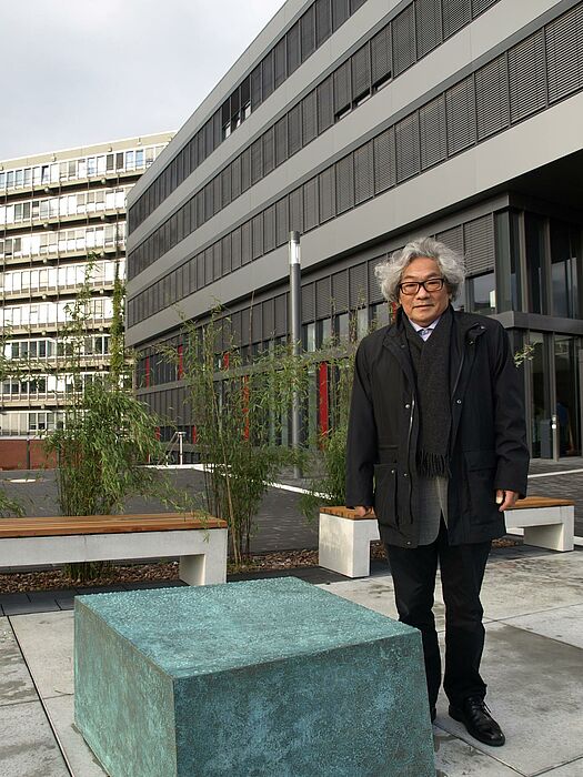 Foto (Bianca Oldekamp): Prof. Yuji Takeoka neben einem der fünf Bronzeskulpturen, die die fünf Fakultäten der der Universität Paderborn verkörpern sollen.