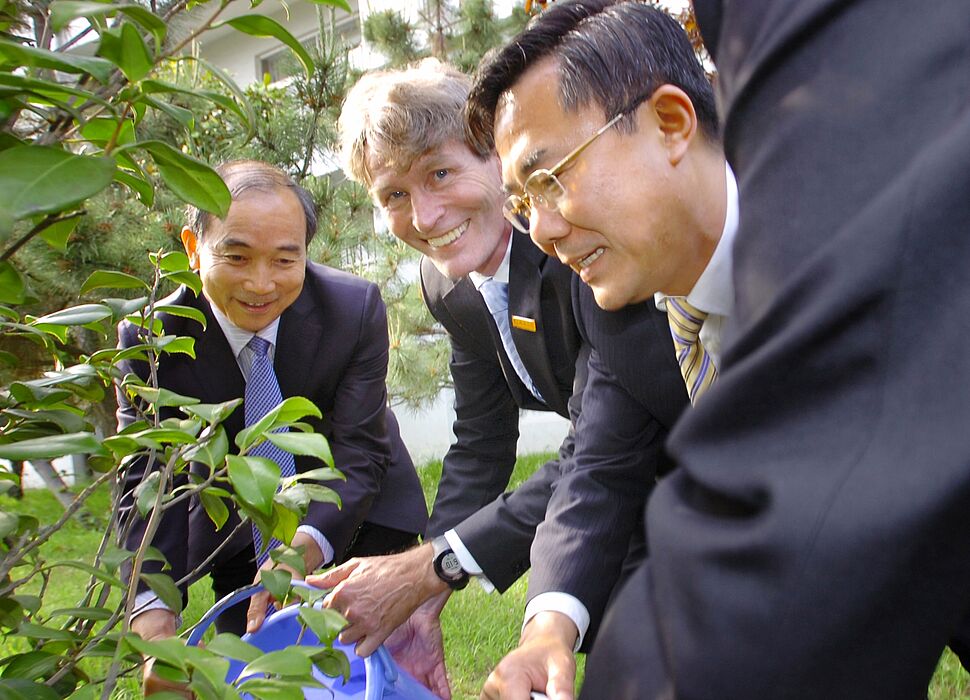 Prof. Dr. Nikolaus Risch und Prof. Dr. Ma Lianxiang (rechts) gießen den vor einigen Jahren gemein-sam in Qingdao gepflanzten Baum als Symbol für die Weiterentwicklung der vor mehr als 10 Jahren gestarteten erfolgreichen Kooperation im Maschinenbau.