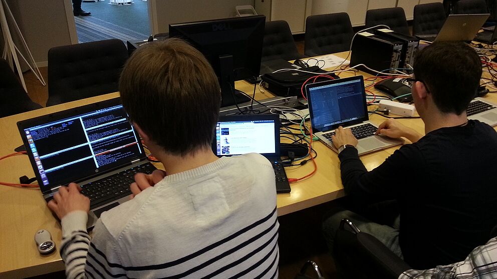 Foto (Matthias Keller): Studierende und Mitarbeiter des Projektes ComGreen testen, wie Optimierungsalgorithmen im Testbett laufen.