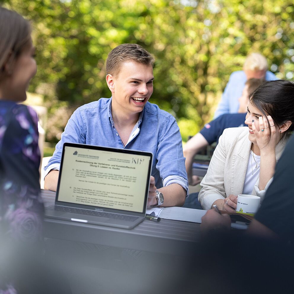 Lächelnde Studierende beim gemeinsamen Lernen mit ihren Laptops