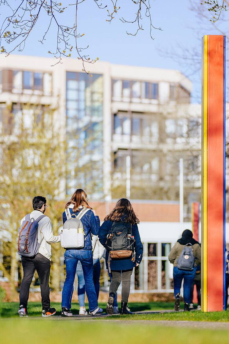 Eine Gruppe Studierender läuft über den Campus der Universität Paderborn auf das Audimax zu.