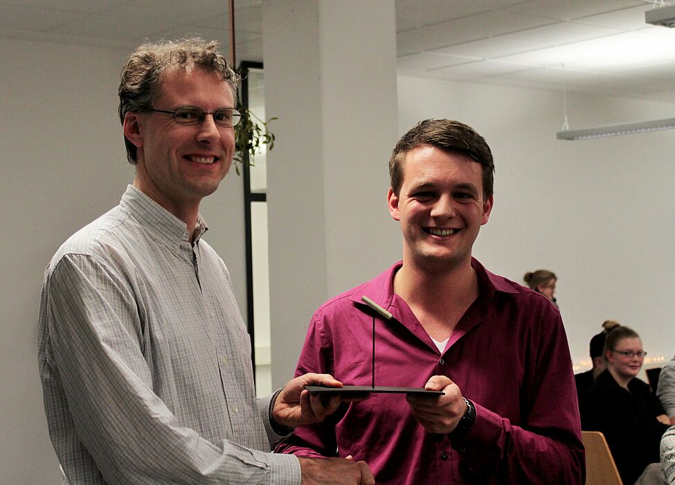 Foto (Department Physik): Prof. Dr. Arno Schindlmayr (li.) freut sich über die „Goldene Kreide“ für die beste Lehrveranstaltung, die ihm von Carsten Müller stellvertretend für die Fachschaft Physik überreicht wird.