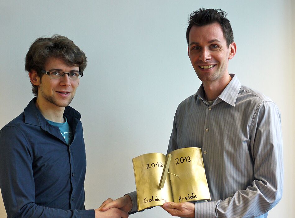 Foto (Universität Paderborn, Heike Probst): Prof. Dr. Thomas Zentgraf (rechts) freut sich mit Philip Heringlake über die „Goldene Kreide“ für die beste Lehrveranstaltung.