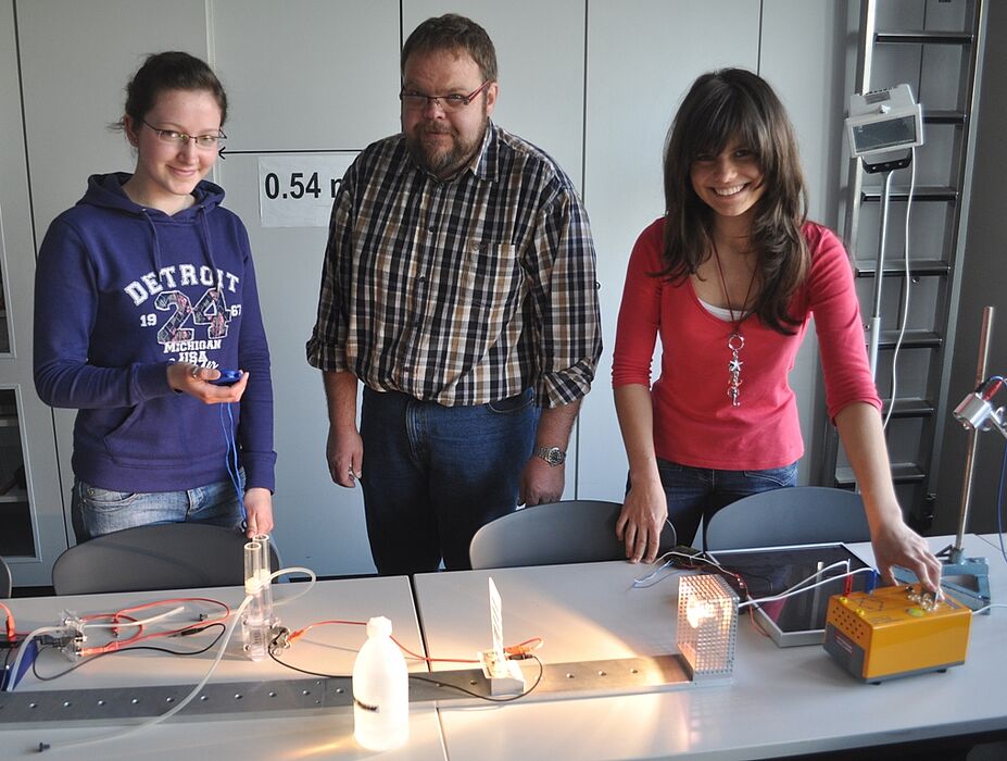 Foto (Universität Paderborn, Mark Heinemann): Stefanie (v. l.) und Jacqueline ließen sich von Wilfried Bröckling zeigen, wie der Strom in die Steckdose kommt.