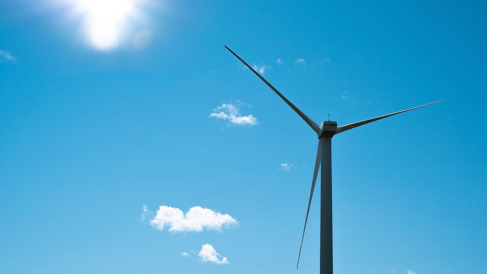 Ein Windrad im blauen Himmel, drum herum ein paar weiße Wolken