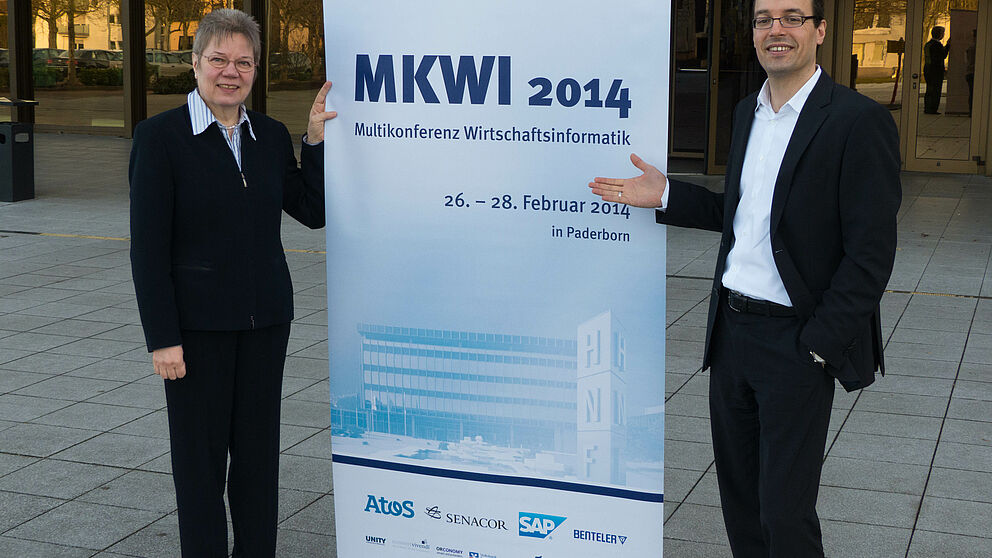 Foto (Universität Paderborn): Die Tagungsleiter Prof. Dr. Leena Suhl und Prof. Dr. Dennis Kundisch präsentieren das Programm der Multikonferenz Wirtschaftsinformatik (MKWI).