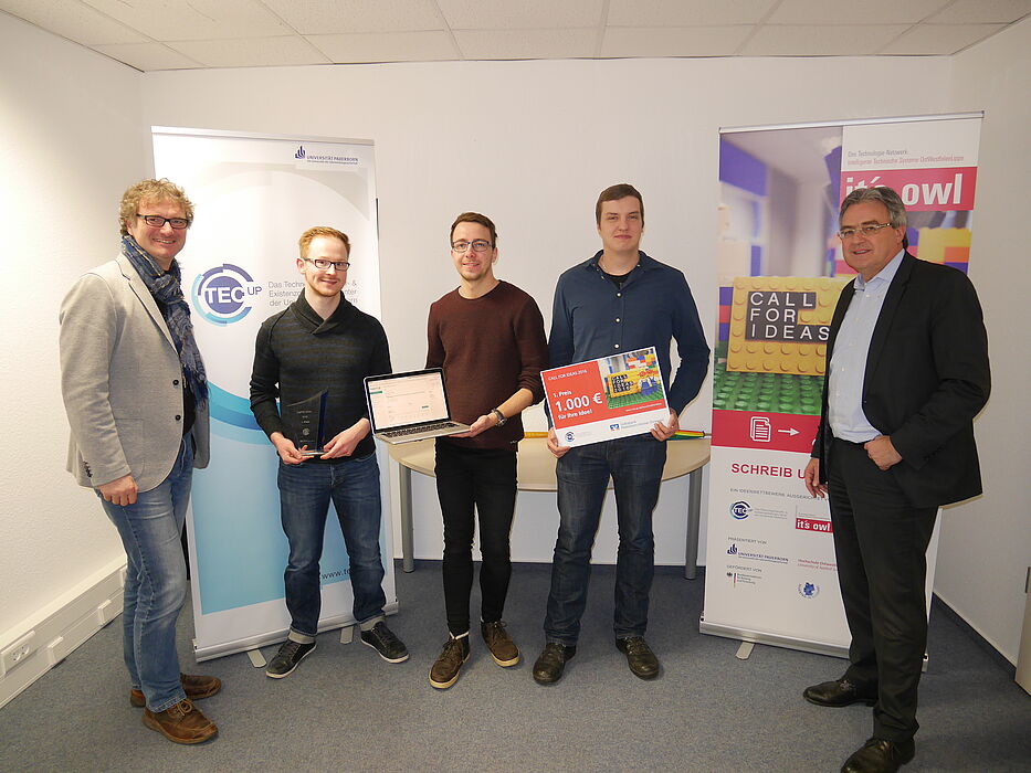 Foto (TecUP, Universität Paderborn): Zu Besuch bei dem Gewinnerteam 2016 Philipp Bednarek (2. v. l.), Christoph Bach (m.) und Marcel Hartmann (2. v. r.) – Rüdiger Kabst (l.) und Karl-Heinz Rawert (r.) freuen sich über die Fortschritte des jungen Star