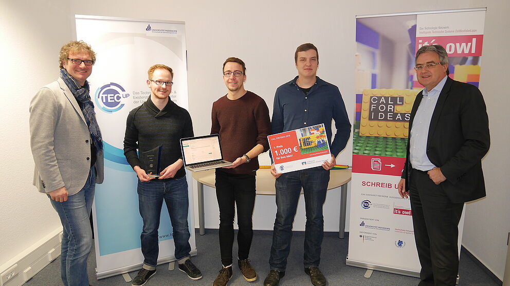 Foto (TecUP, Universität Paderborn): Zu Besuch bei dem Gewinnerteam 2016 Philipp Bednarek (2. v. l.), Christoph Bach (m.) und Marcel Hartmann (2. v. r.) – Rüdiger Kabst (l.) und Karl-Heinz Rawert (r.) freuen sich über die Fortschritte des jungen Star